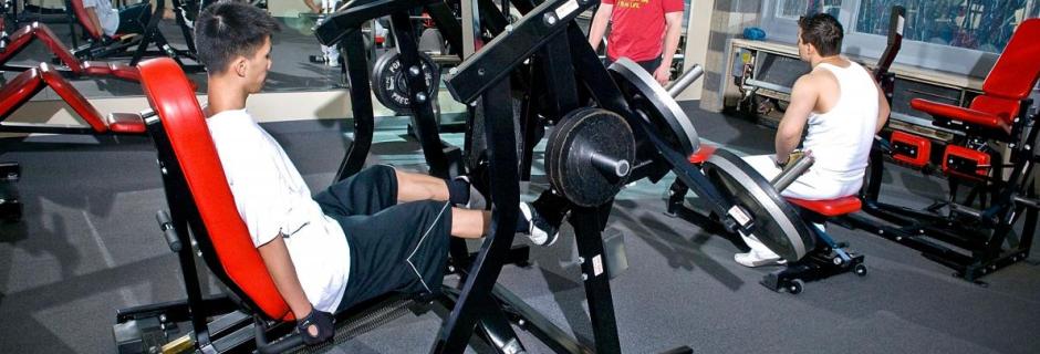 Student using athletic equipment in gym at Community College of Philadelphia. men working out in weight room