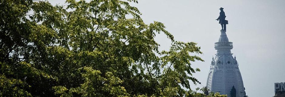 A tree in front of the top of city hall with William Penn from the  direction of CCP.