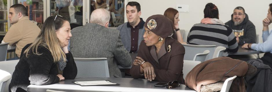 People sitting at tables at CCP's Women's Outreach and Advocacy Center.