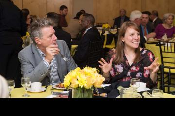 Two attendees chat over breakfast.