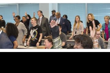 The standing audience smiles in response to Mr. Sygielski's speech.