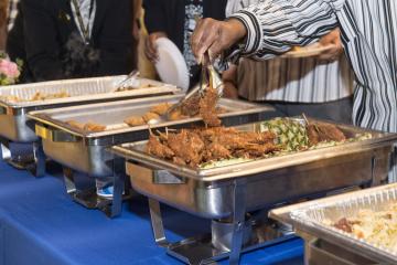 An attendee dishes chicken screwers