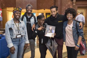 Students smile and pose for the camera holding up the print publication