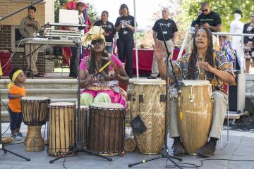 A woman and man drum while a small child looks on.