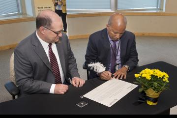 Dr. Generals signs the agreement as President Hawkinson looks on.