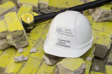 A ceremonial sledge hammer and hard hat sit on the ceremonial broken bricks.