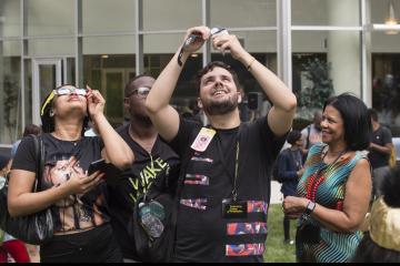 Eclipse Party goers view the eclipse through eclipse glasses.