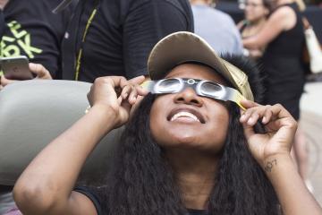 An Eclipse Party goer views the eclipse through eclipse glasses.