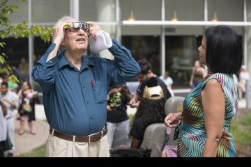 Vice President of Strategic Initiatives, Judy Gay, shares her eclipse glasses with a party goer.