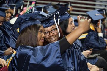Two graduates take a selfie.
