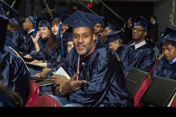 A graduate smiles for the camera and gives a peace sign.