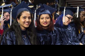 Two graduates smile for the camera.