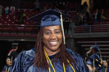 A graduate holds up her diploma.