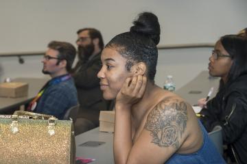 A student audience member listens.