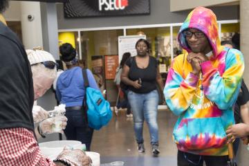 A student wearing a hoodie that matches the colors of the water ice waits for his turn.