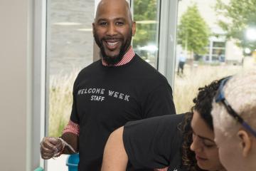 A Welcome Week Staff member smiles for the camera in between serving water ice.